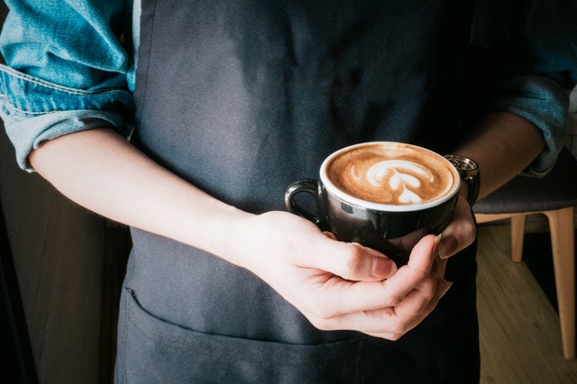 Waiter holding coffee in hands