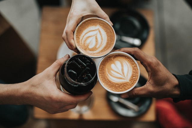 Three hands holding coffee cups together